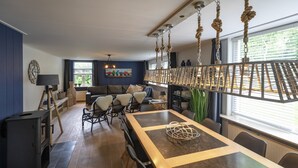 A modern living room with a large dining table, sofas, and a hanging light fixture. - Farmhouse in North Holland Near Beaches (Sint Maartensvlotbrug)