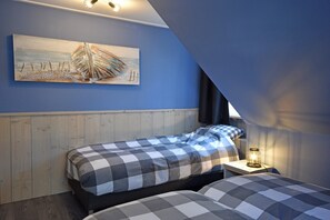 A bedroom with a checkered bedspread, a wooden headboard, a painting of a boat on the wall, and a bedside lamp. - Farmhouse in North Holland Near Beaches (Sint Maartensvlotbrug)