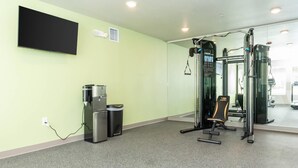 A gym with exercise equipment, a water dispenser, and a TV on the wall.