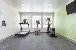 Un gimnasio con cinta de correr, elíptica y bicicleta estática.