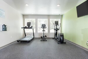 Un gimnasio con cinta de correr, elíptica y bicicleta estática.