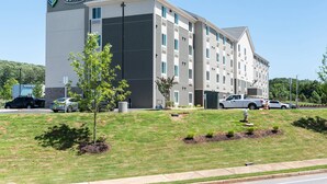 A multi-story hotel with a flat roof and a sign reading 'Woodspring Suites.'