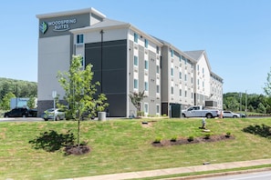 Un hotel de varios pisos con techo plano y un letrero que dice 'Woodspring Suites'.