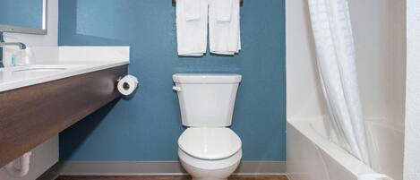 Ein Badezimmer mit Toilette, einem Holzkosmetikschrank, blauer Wand und einer Duschvorhang.