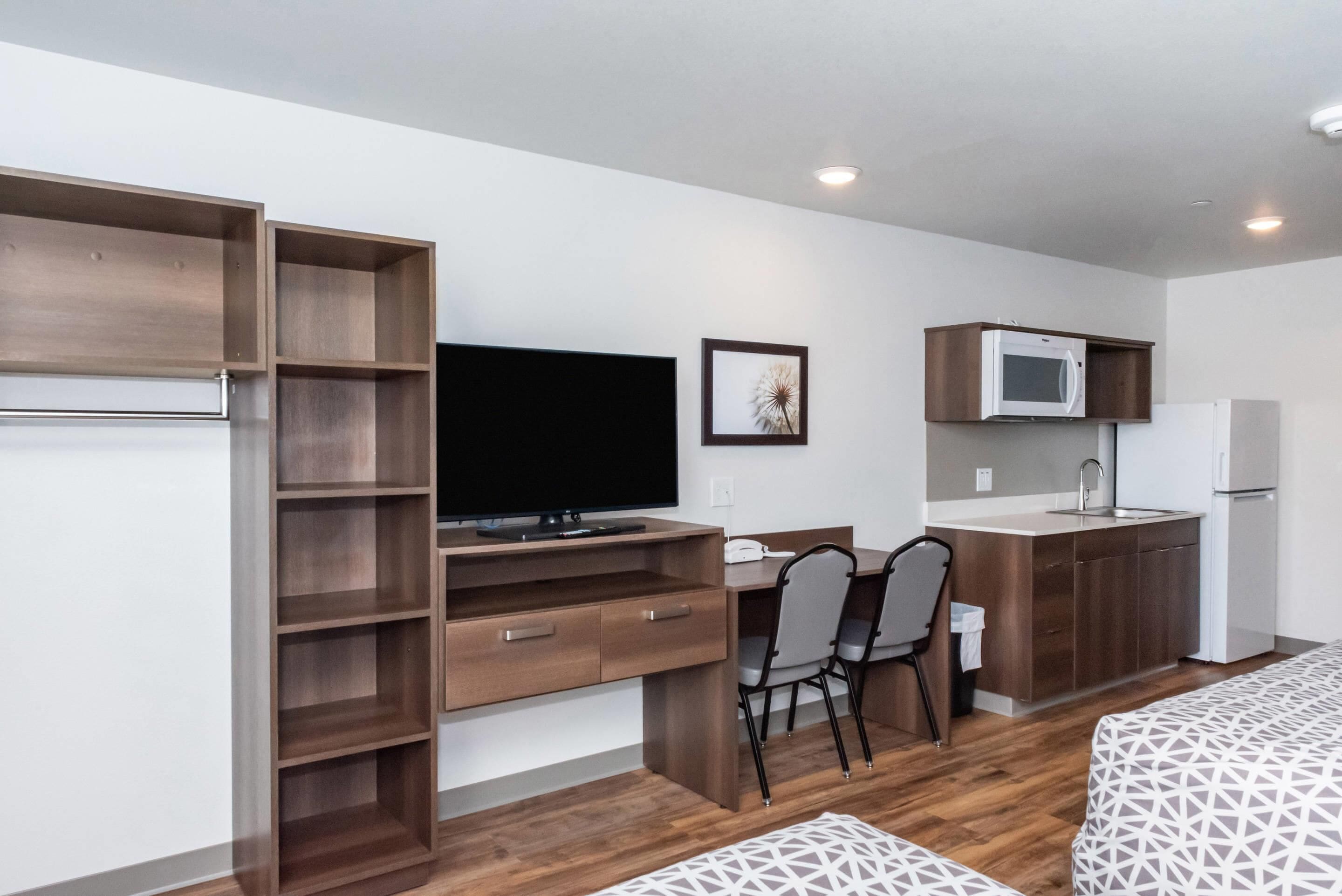 A compact kitchenette with a microwave, refrigerator, and a small dining area with a chair.