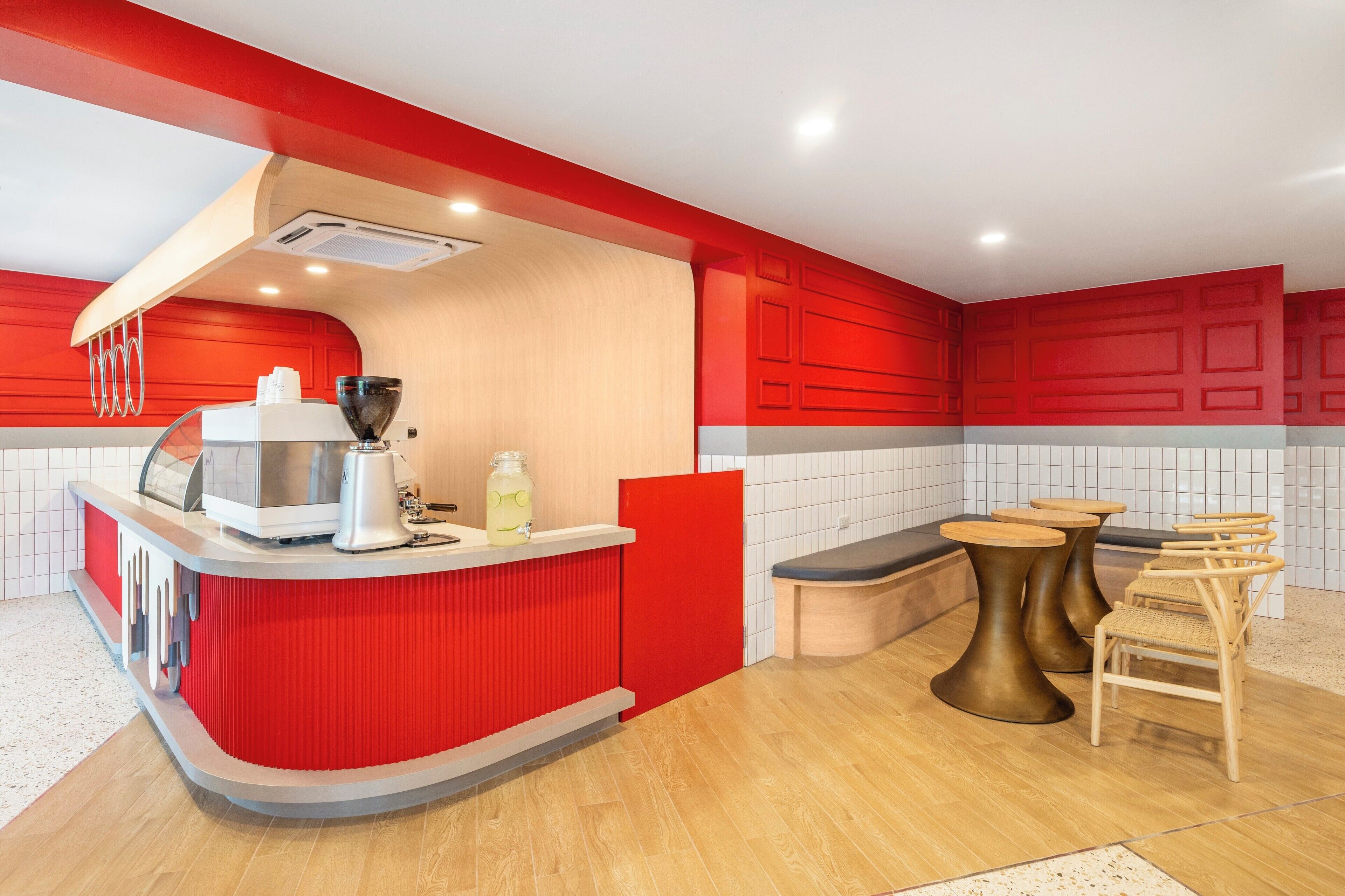 A kitchen with red cabinetry, a white countertop, and a wooden floor.