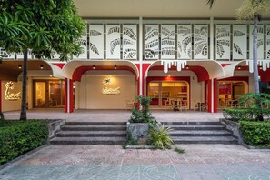 En hotellentrén med en palm, några trappsteg och en skylt med texten ”Cummer Sea Palace”.