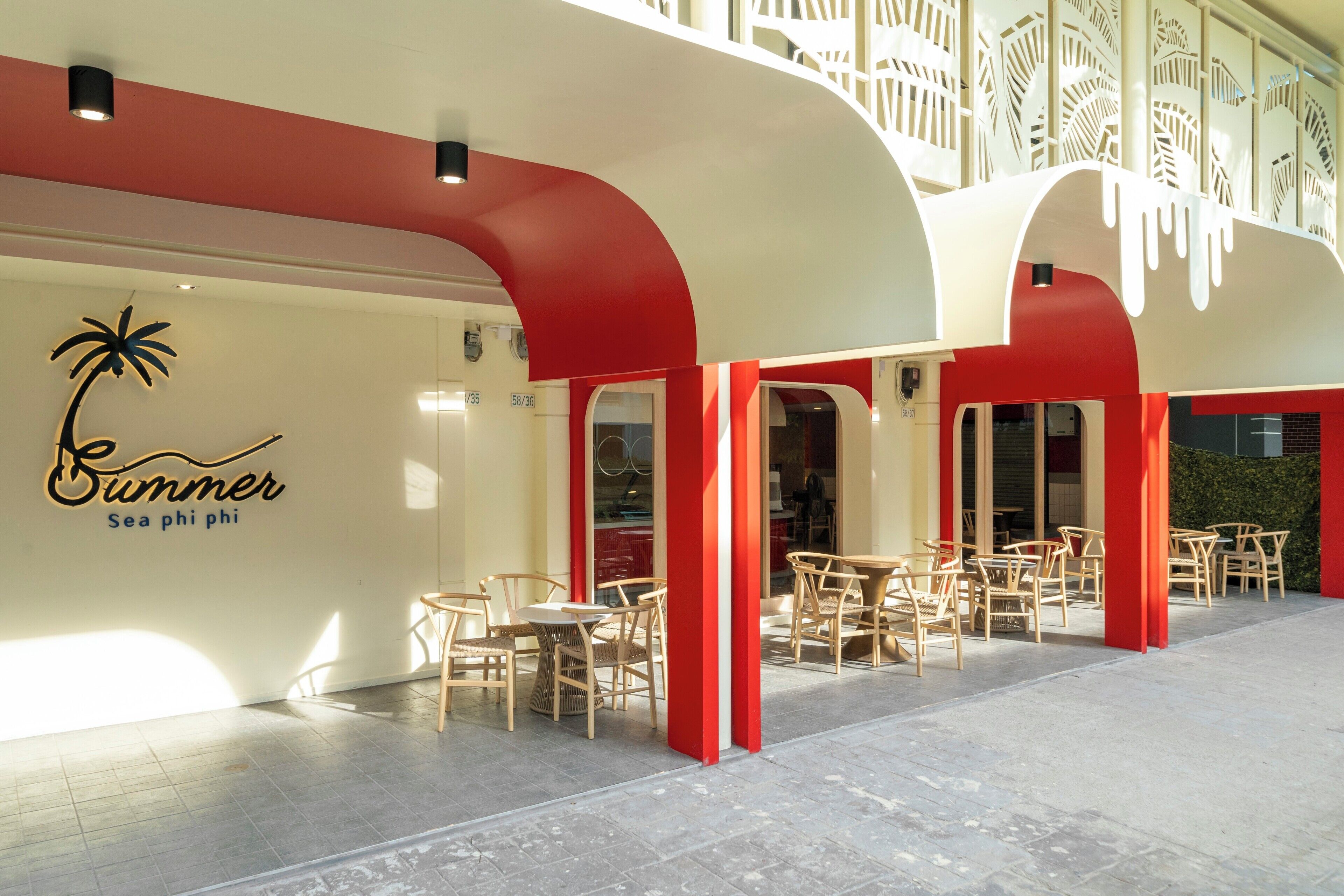 A restaurant with outdoor seating, red and white architecture, and a sign reading "Summer Sea phi phi".