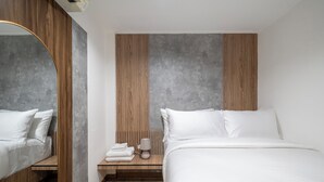 Een moderne hotelkamer met een groot bed, een nachtkastje met een lamp en een spiegel.