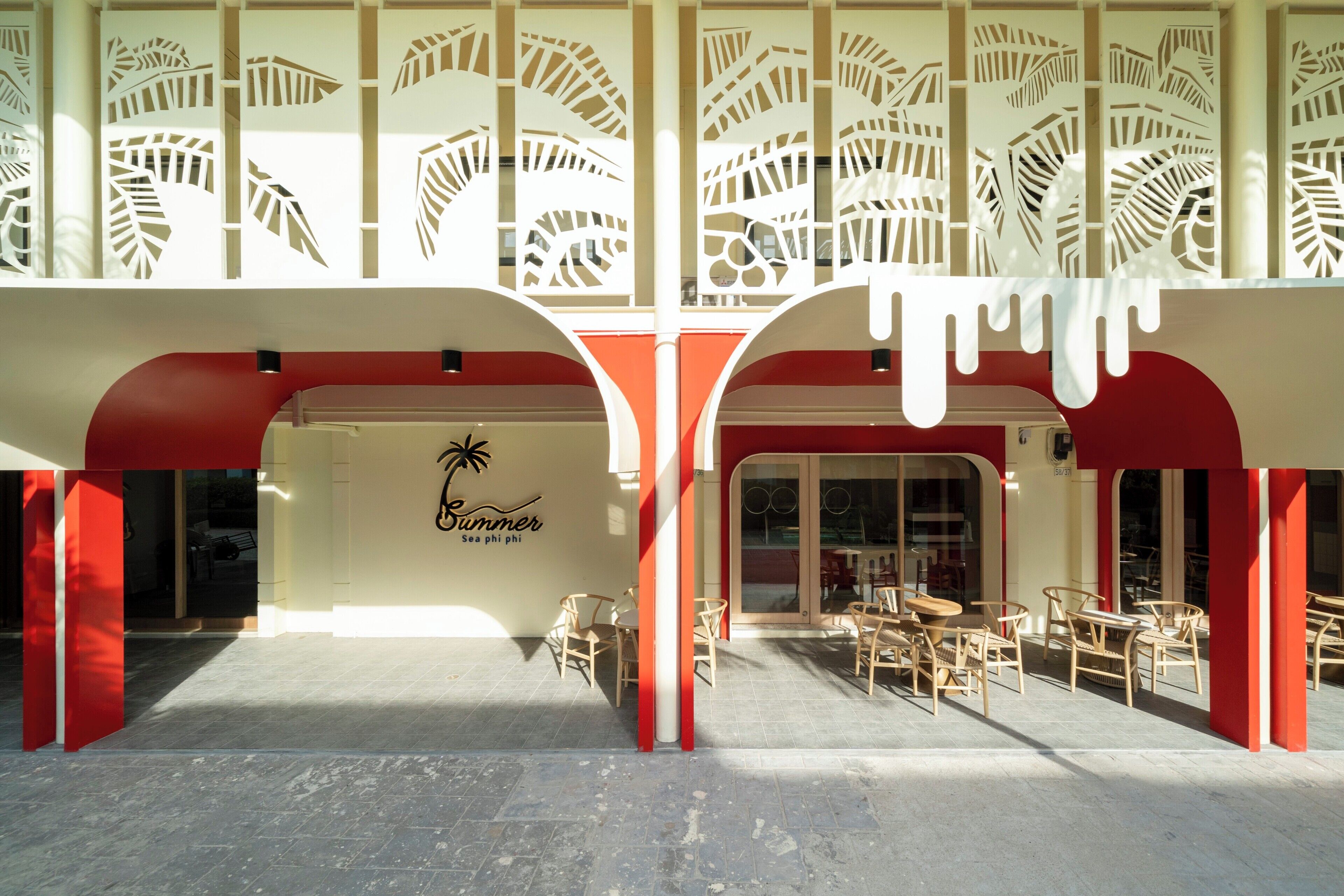Un edificio con diseño tropical, que presenta motivos de hojas de palmera en la fachada y un letrero que dice 'Summer Sea Phi Phi'.