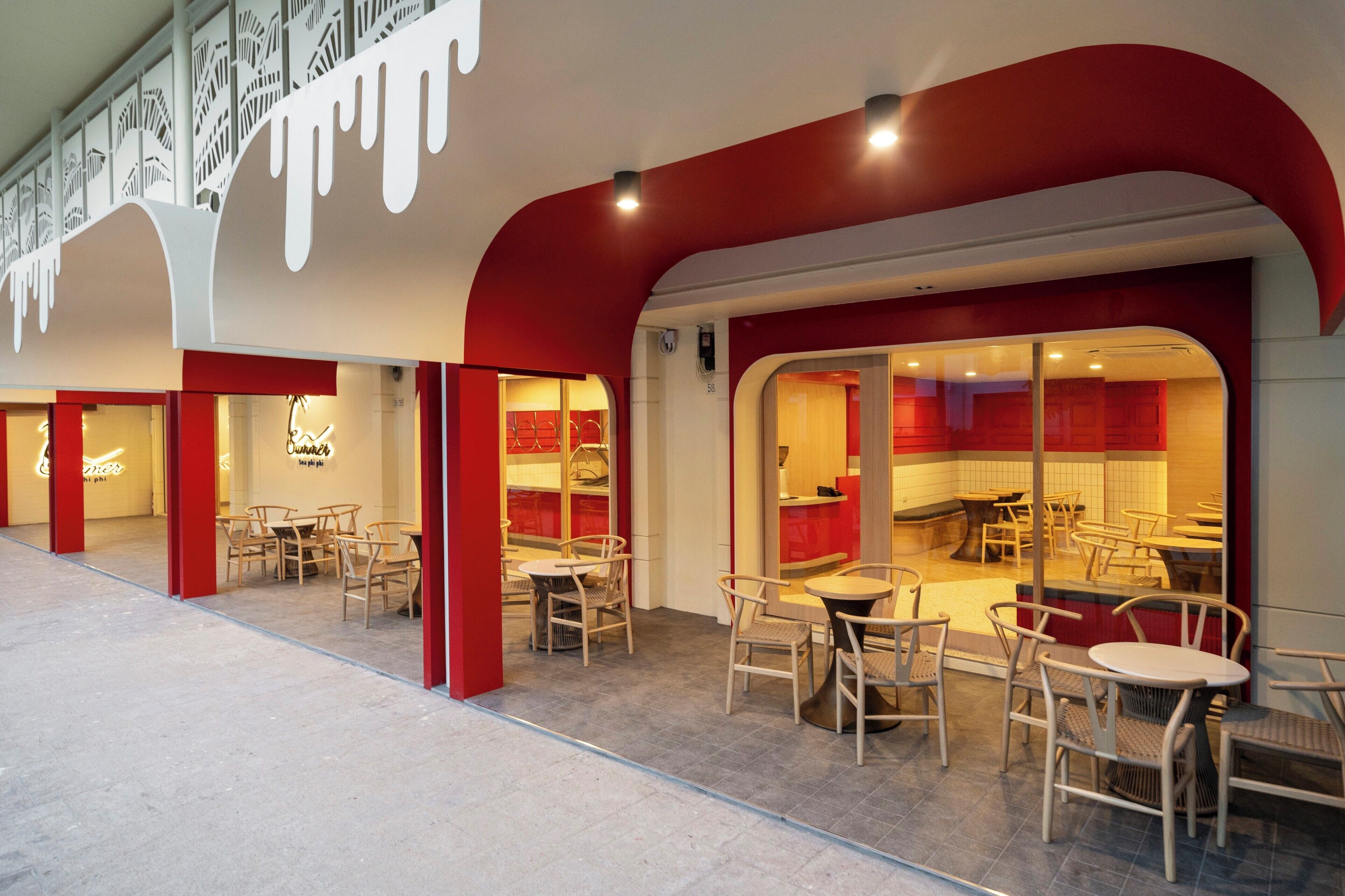 An indoor dining area with red and white decor, multiple tables and chairs, and a modern architectural design.