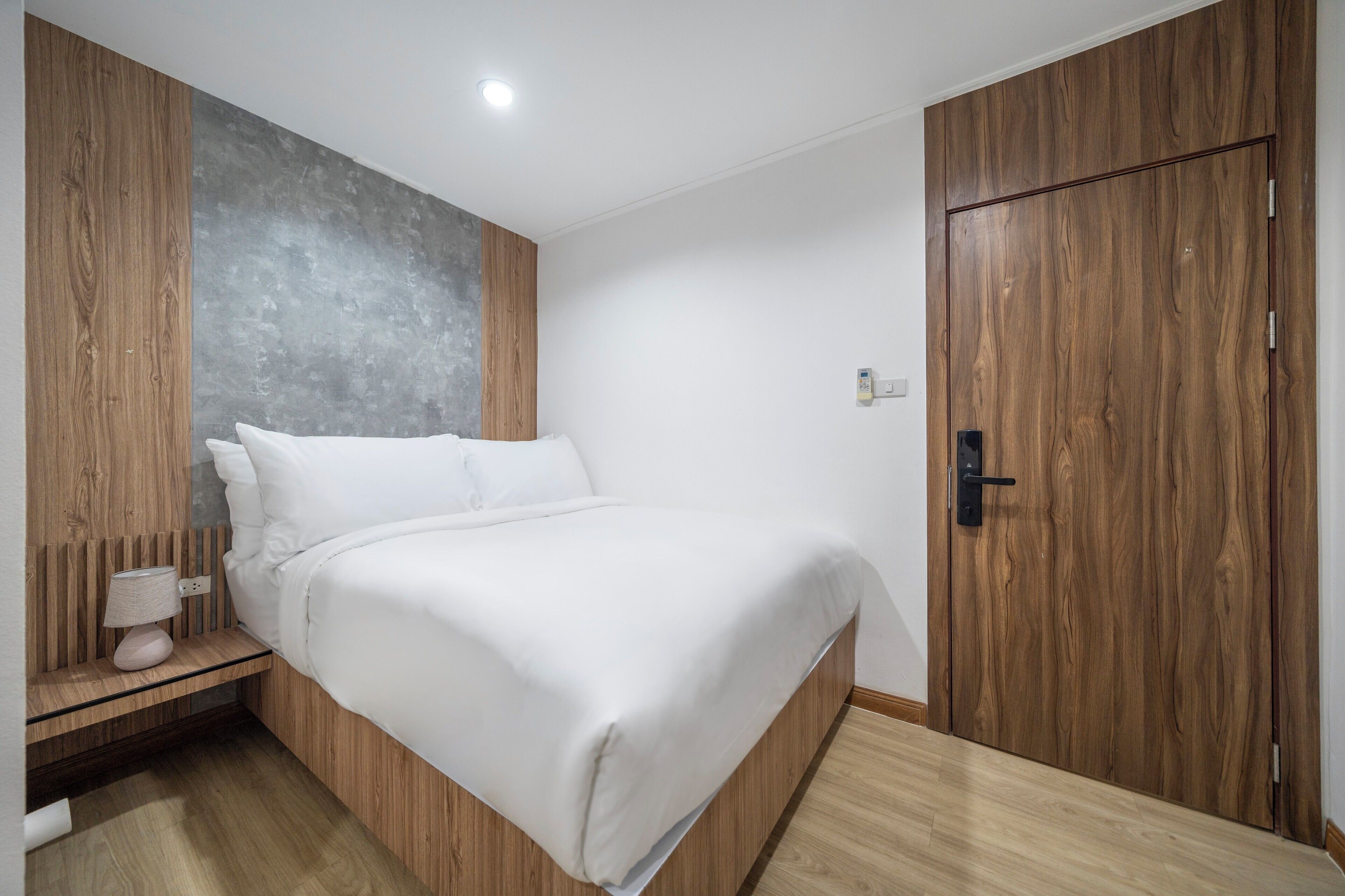 Un dormitorio moderno con estructura de cama de madera, pared de acento gris y armario de madera.
