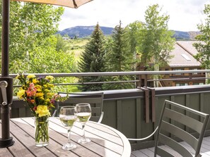 A balcony with a table, two wine glasses, and a vase of flowers. - Villas at Snowmass Club - 1207 (Snowmass Village)