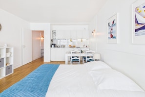 Une chambre avec un lit, un tapis bleu, un coin cuisine et un espace repas.