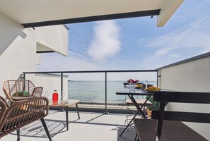 A balcony with a table and chairs, a view of the sea, and a bottle of red drink. - -BLUE- STUDIO AVEC VUE MER ET PARKING (Concarneau)