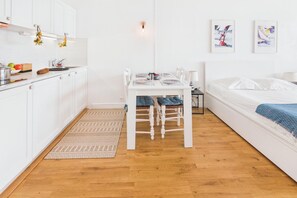 A compact, well-lit room with a kitchenette, dining area, and a bed.