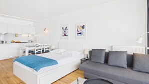 A modern, white-themed bedroom with a bed, a grey sofa, and a small table. - -BLUE- STUDIO AVEC VUE MER ET PARKING (Concarneau)