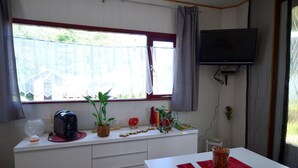A room with a white desk, a TV mounted on the wall, a window with curtains, and a small table with a remote control. - Apartment in Meisberg With In-house Catering (Meisburg)