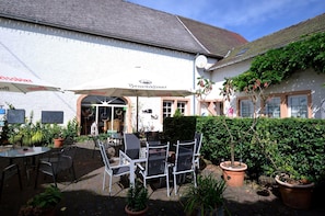 An outdoor seating area with tables and chairs, a white building with a sign reading "Benediktiner," and potted plants. - Apartment in Meisberg With In-house Catering (Meisburg)