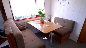 A compact room with a wooden table, two cushioned benches, a potted plant, and a decorative glass object. - Apartment in Meisberg With In-house Catering (Meisburg)