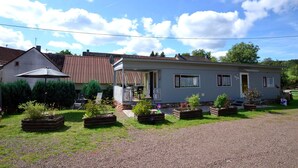 A single-story house with a porch, a satellite dish, and a gravel driveway. - Apartment in Meisberg With In-house Catering (Meisburg)