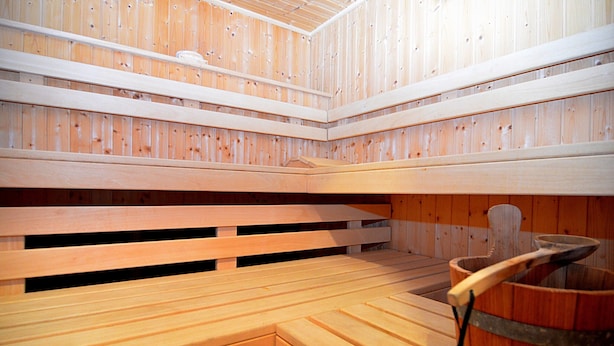 Una sauna con bancos de madera y un cubo de madera.