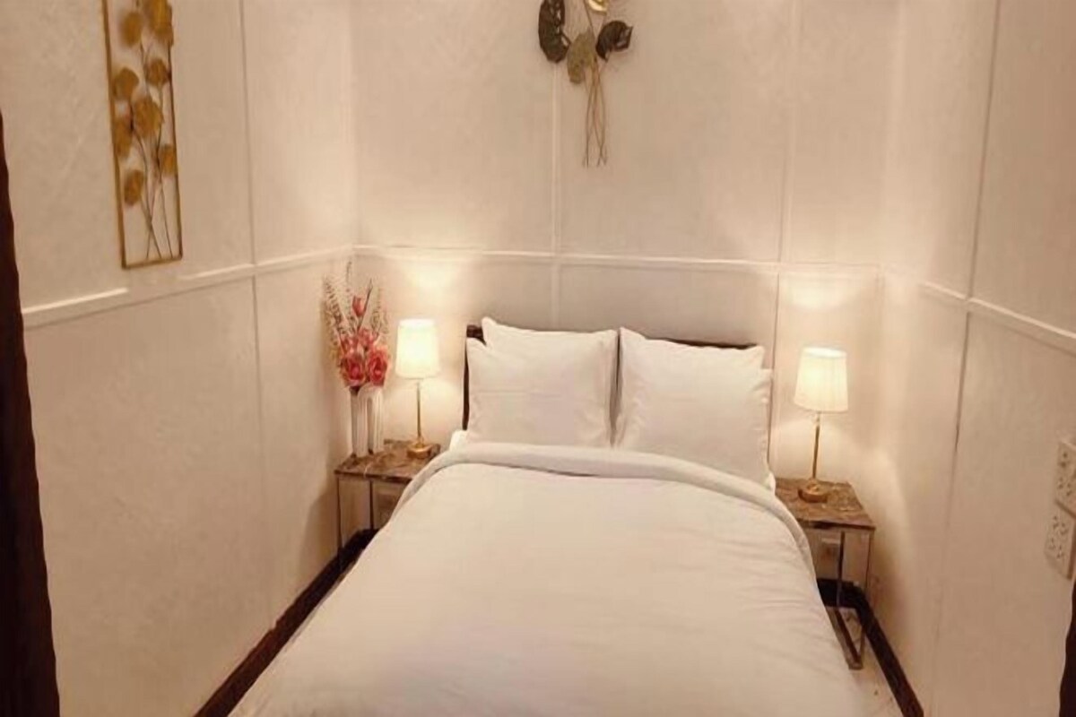 A hotel room with a bed, two bedside tables with lamps, and wall-mounted decor.