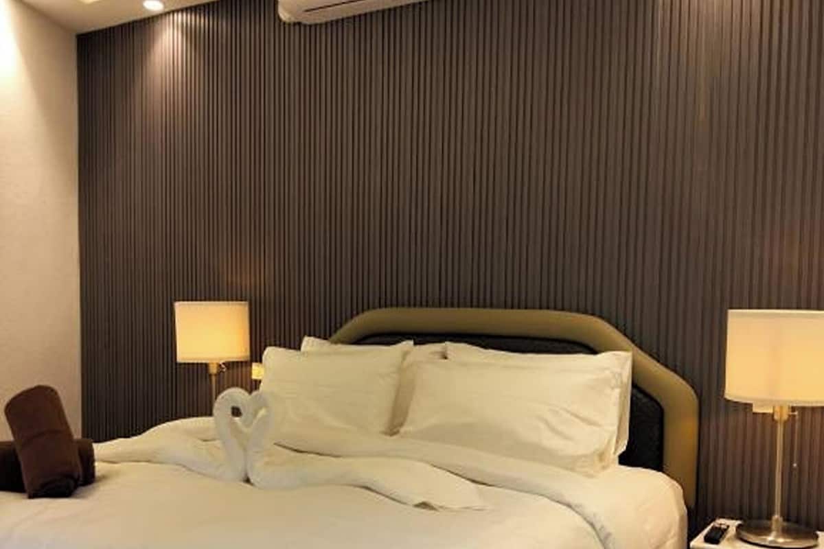 Ein Hotelzimmer mit einem Bett, Nachttischlampen, einer Klimaanlage und einer Wandpaneele.