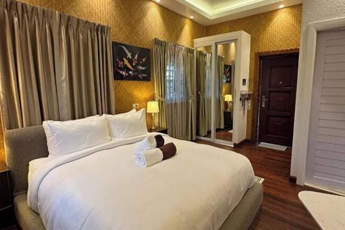 Ein Hotelzimmer mit einem großen Bett, einem Schreibtisch, einem Stuhl, einem Kleiderschrank und einer Tür.