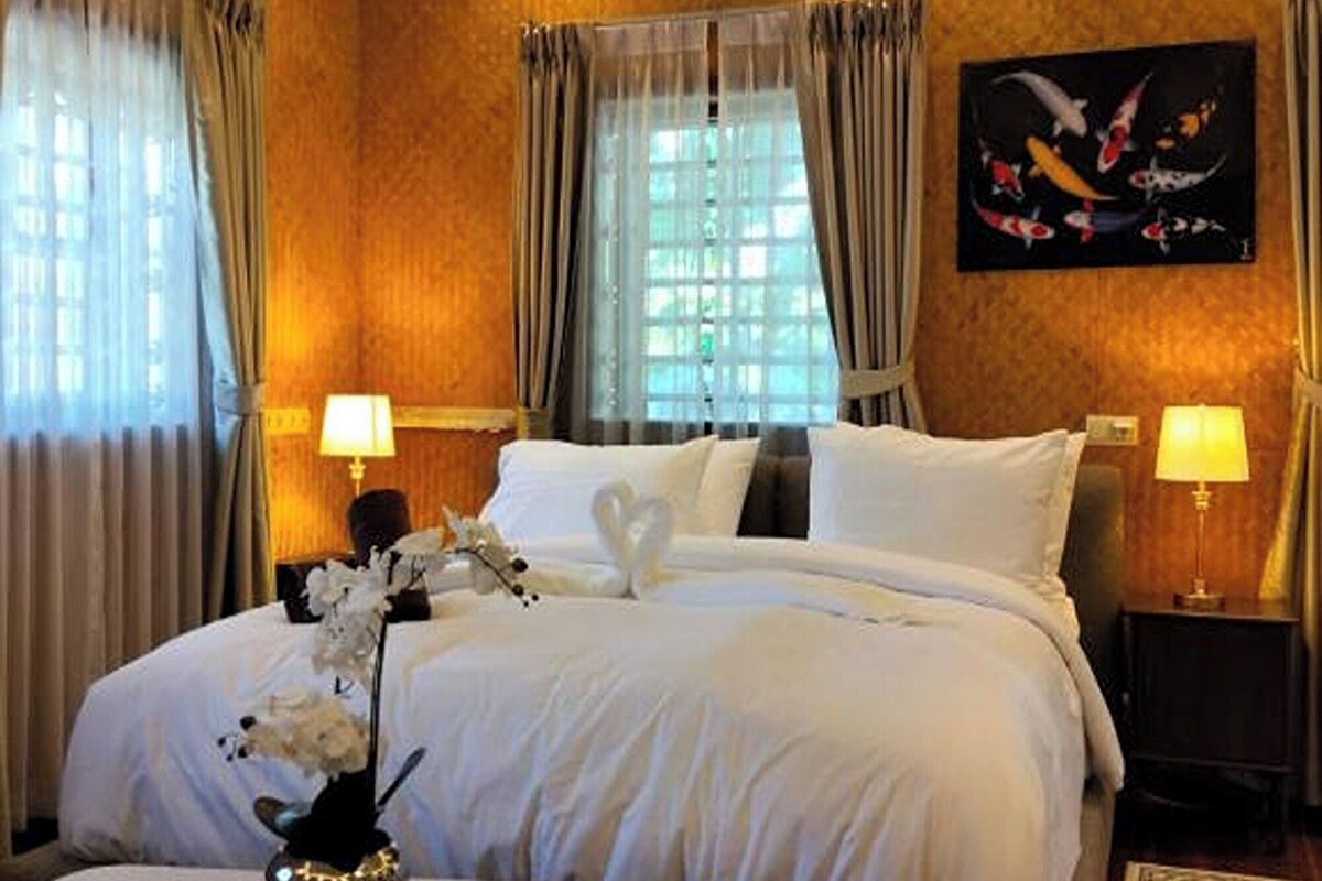 A hotel room with a large bed, two bedside tables, a white coffee table, and a painting on the wall.