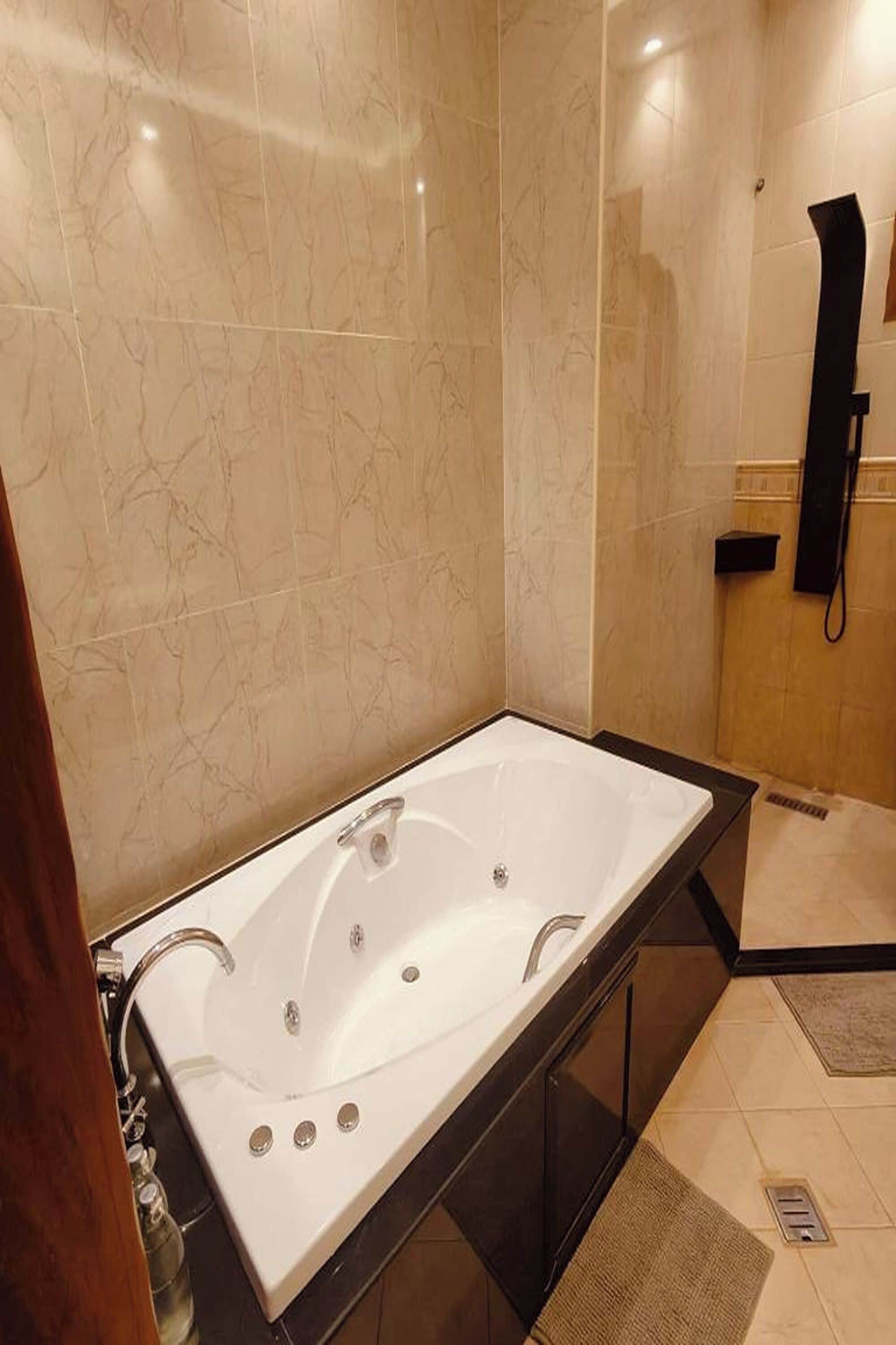 Un baño moderno con una bañera grande, un tocador con espejo y un teléfono.
