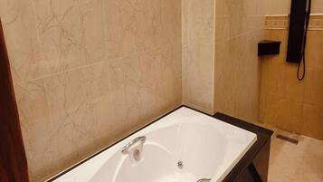 Un baño moderno con una bañera grande, un tocador con espejo y un teléfono.