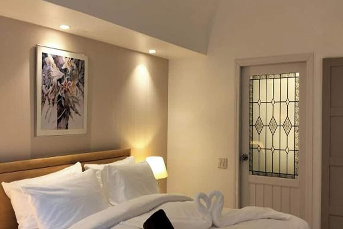 Ein Hotelzimmer mit Bett, Deckenventilator, einer Tür mit Glasfenster und einer Wandleuchte.