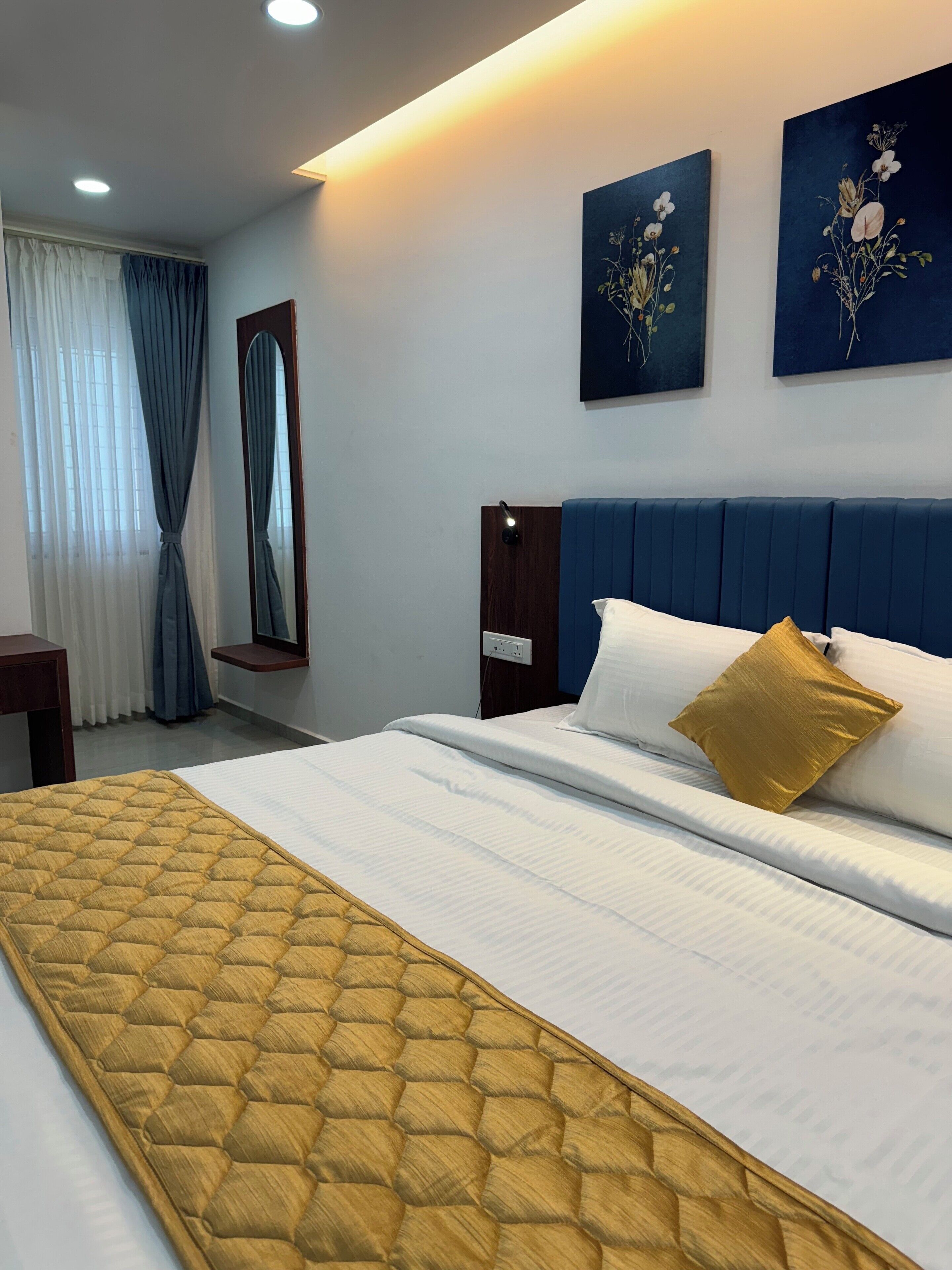 Una camera d'albergo con un letto, un comodino, uno specchio e due quadri appesi al muro.