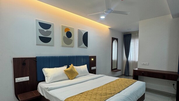 Una habitación de hotel moderna con una cama grande, una mesita de noche, un escritorio y un ventilador de techo.