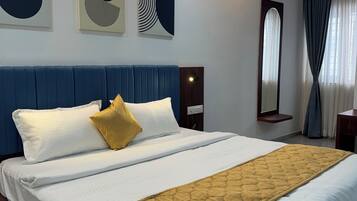 Quarto de hotel com uma cama grande, um ventilador de teto e obras de arte na parede.