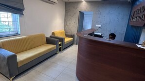 Un área de recepción con un escritorio curvo de madera, un sofá y una silla.