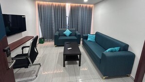 Una sala de estar moderna con un televisor de pantalla plana, dos sofás, una mesa de centro y un ventilador de techo.