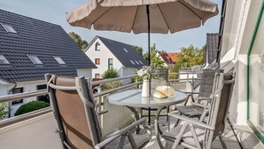 Un balcon avec une table, des chaises et un grand parasol.