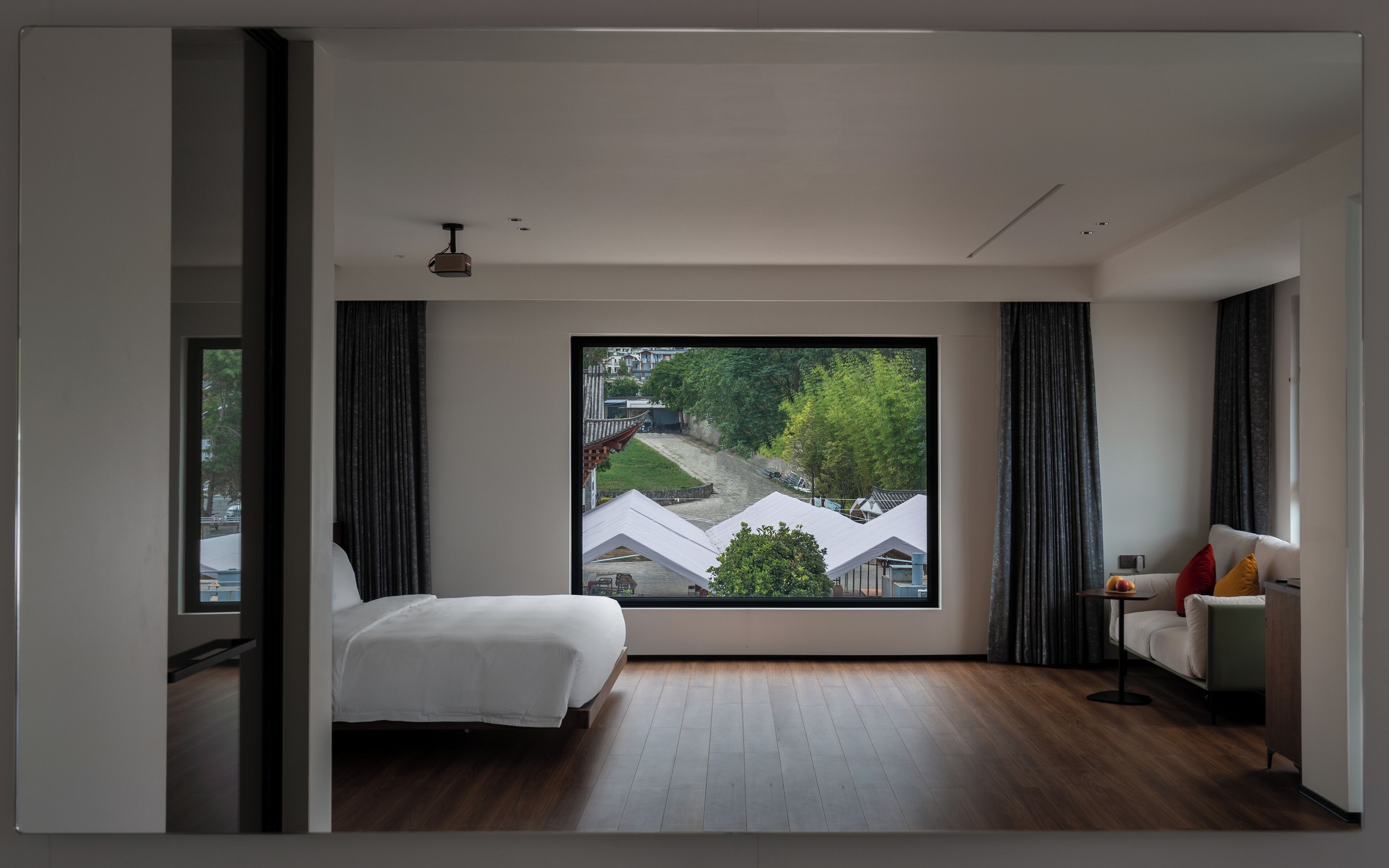Ein modernes Hotelzimmer mit großem Fenster, einem Bett, einem kleinen Tisch und einer Couch.