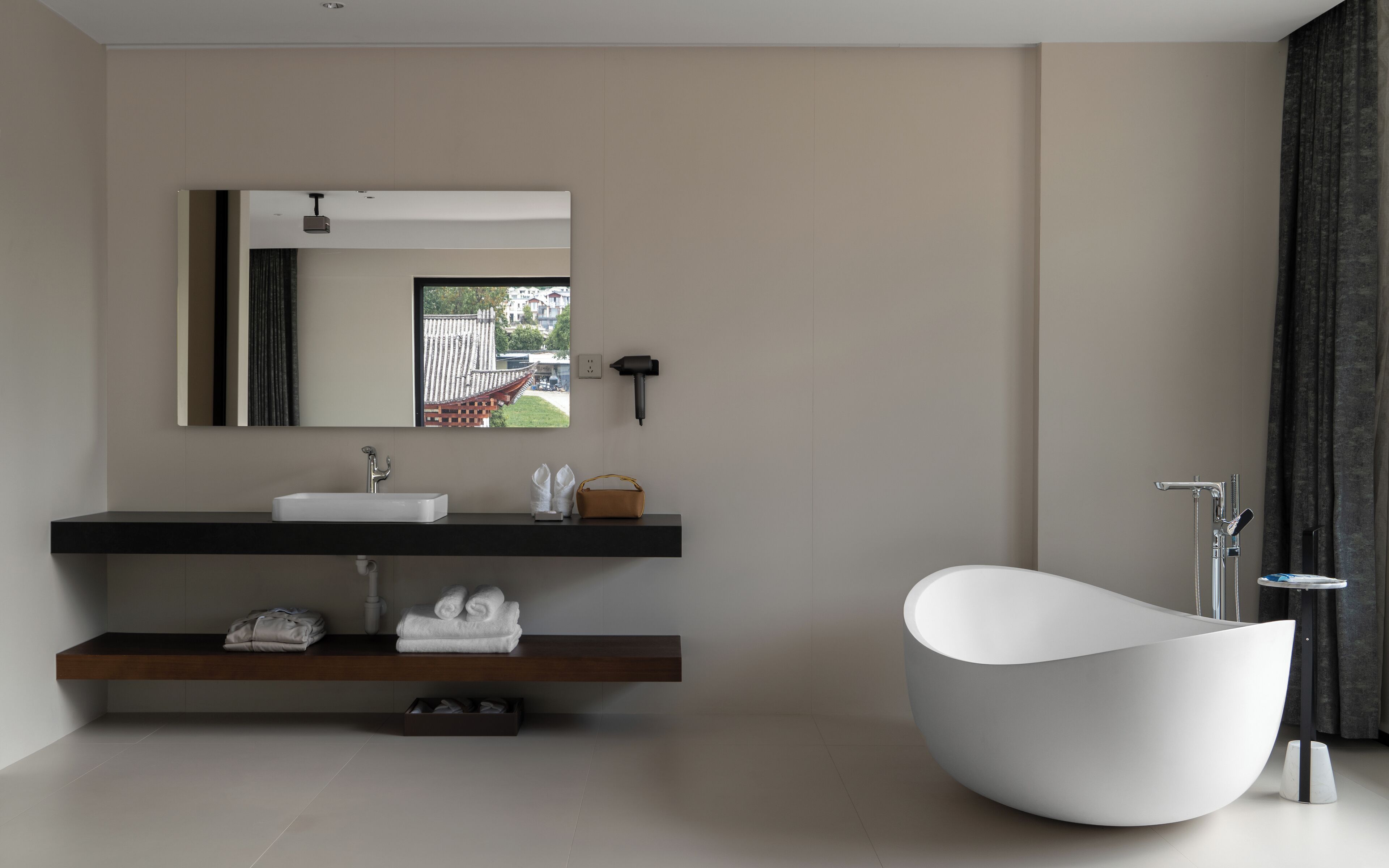 A modern bathroom with a freestanding bathtub, a large mirror, and a minimalist vanity.
