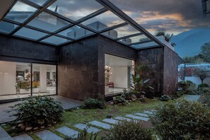 A modern house with a glass roof, a garden with stepping stones, and a view of mountains. - Neo-garden (Dali)