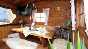 A wooden cabin interior with a wooden dining table, benches, and a TV mounted on the wall. - Apartment in Fugen Near ski Resort (Fuegen)
