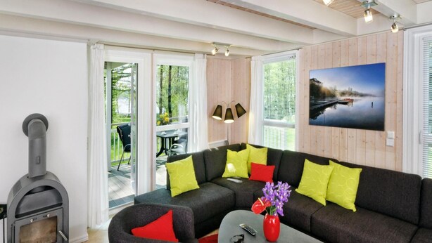 Un salon moderne avec un canapé d’angle, une cheminée et un coin repas visible à travers des portes vitrées.