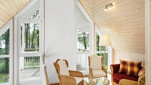 Une pièce chaleureuse, meublée de meubles en osier, avec une table en verre et un canapé rouge.