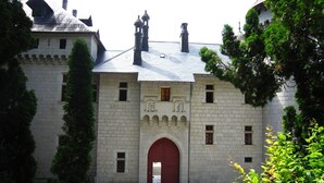 Un bâtiment historique en pierre, doté d’une arche rouge centrale, de nombreuses fenêtres et d’une façade symétrique.