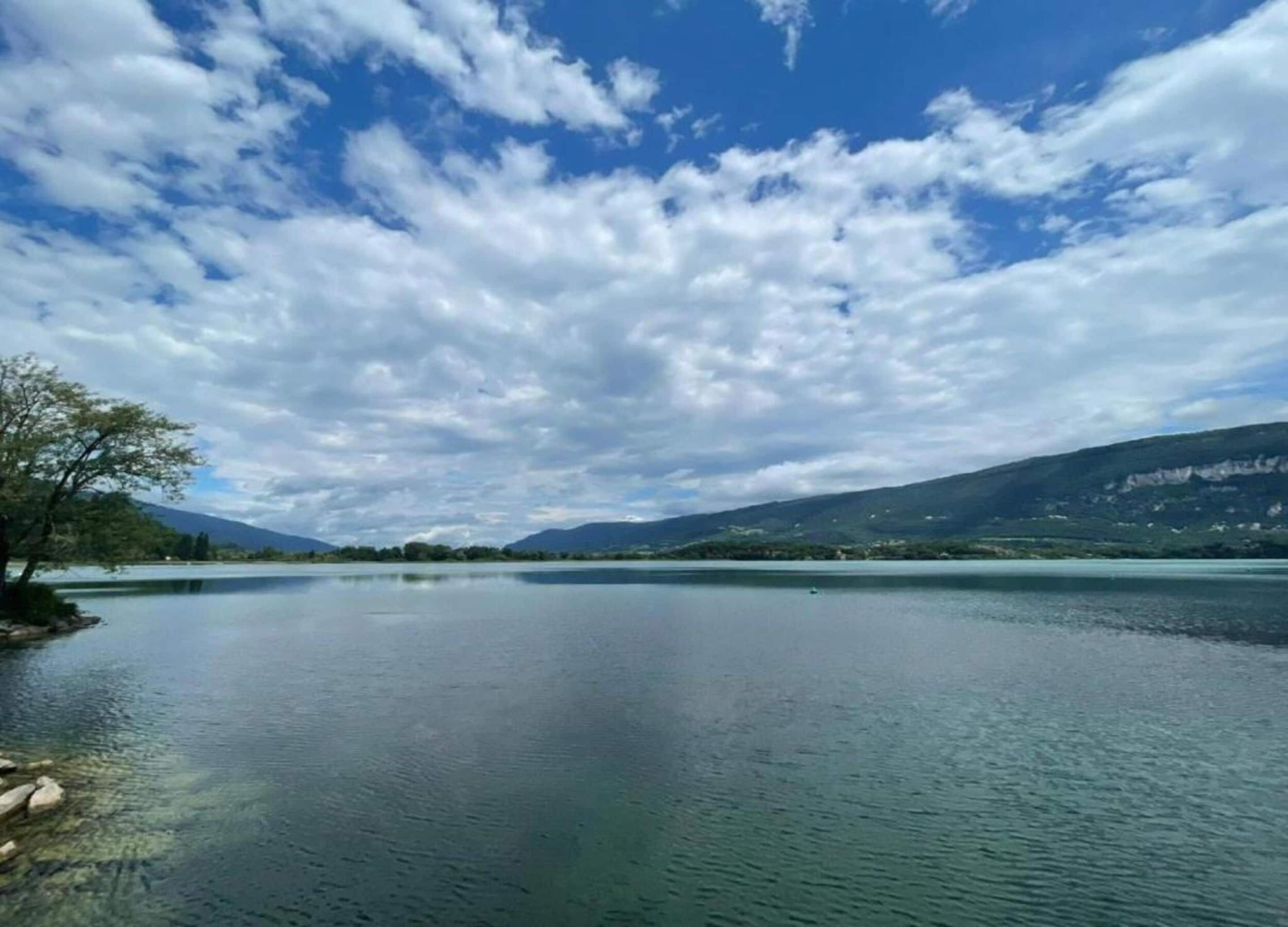 Un lago tranquilo con cielo despejado y montañas al fondo.