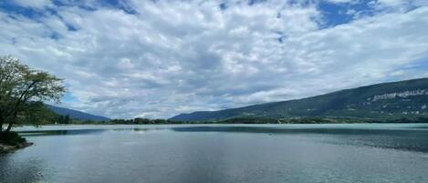 Un lago tranquilo con cielo despejado y montañas al fondo.