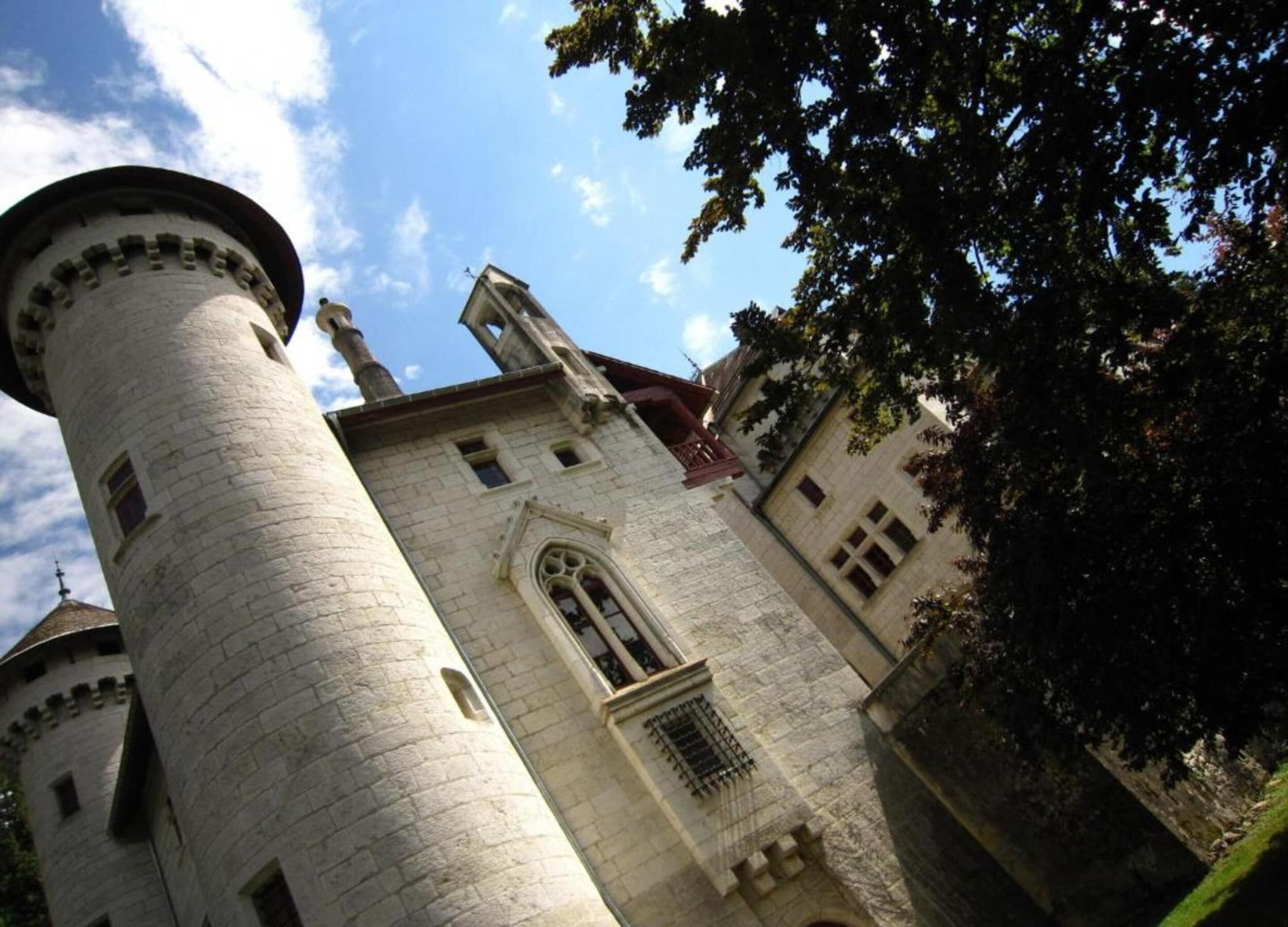 A historic stone tower with a rounded top, a large arched window, and a smaller window with a barred design.