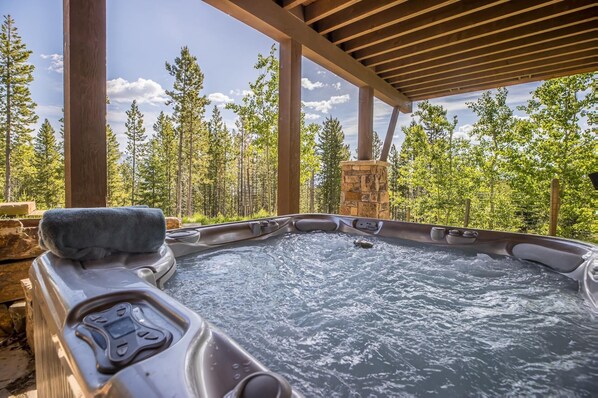 A hot tub with a stone structure in the background, surrounded by trees.